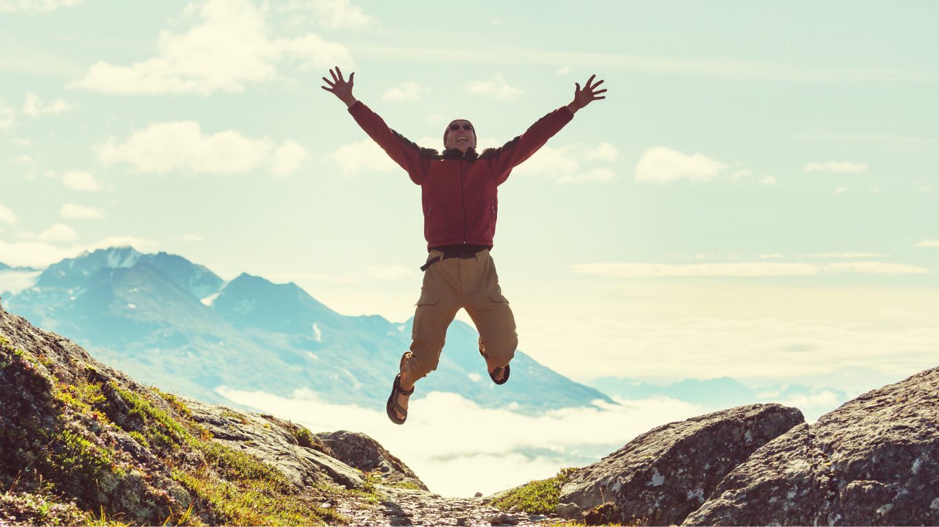 man jumping up looking at a mountain view