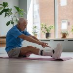 old man on the floor trying to touch his toes
