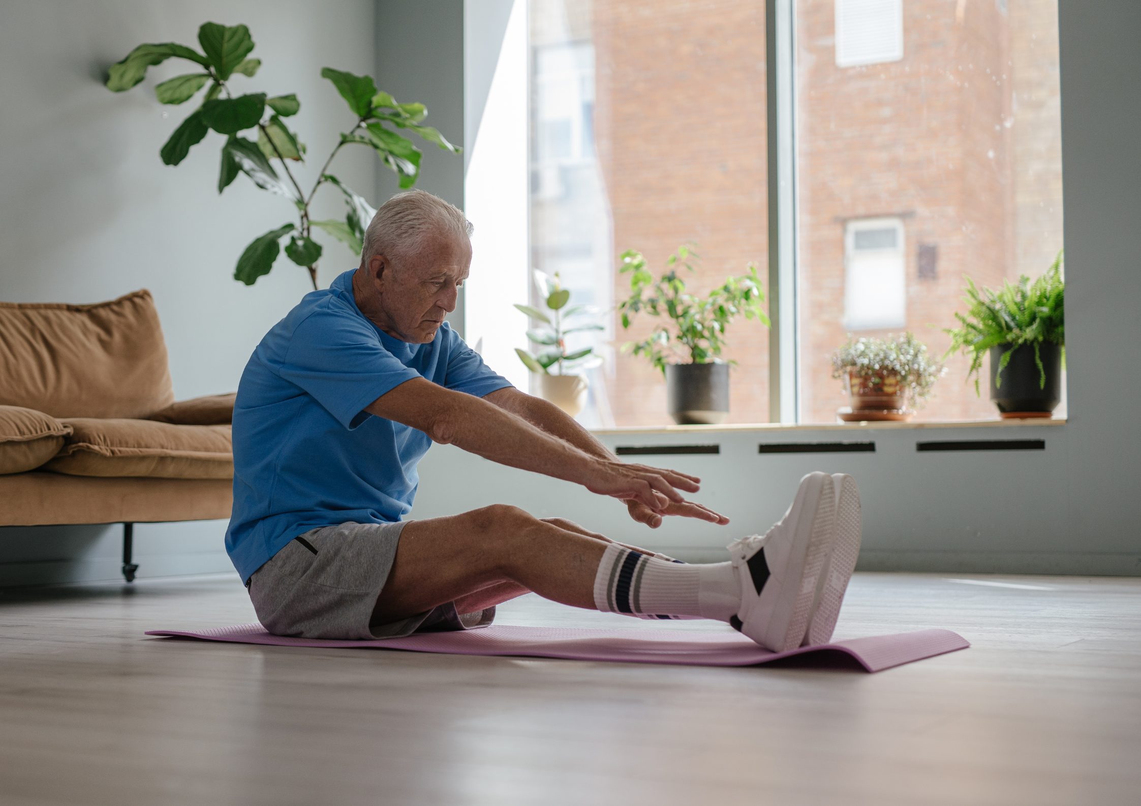 old man on the floor trying to touch his toes
