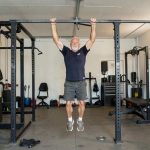 old man hanging from a pull up bar.