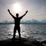 man starring at the sun by the ocean