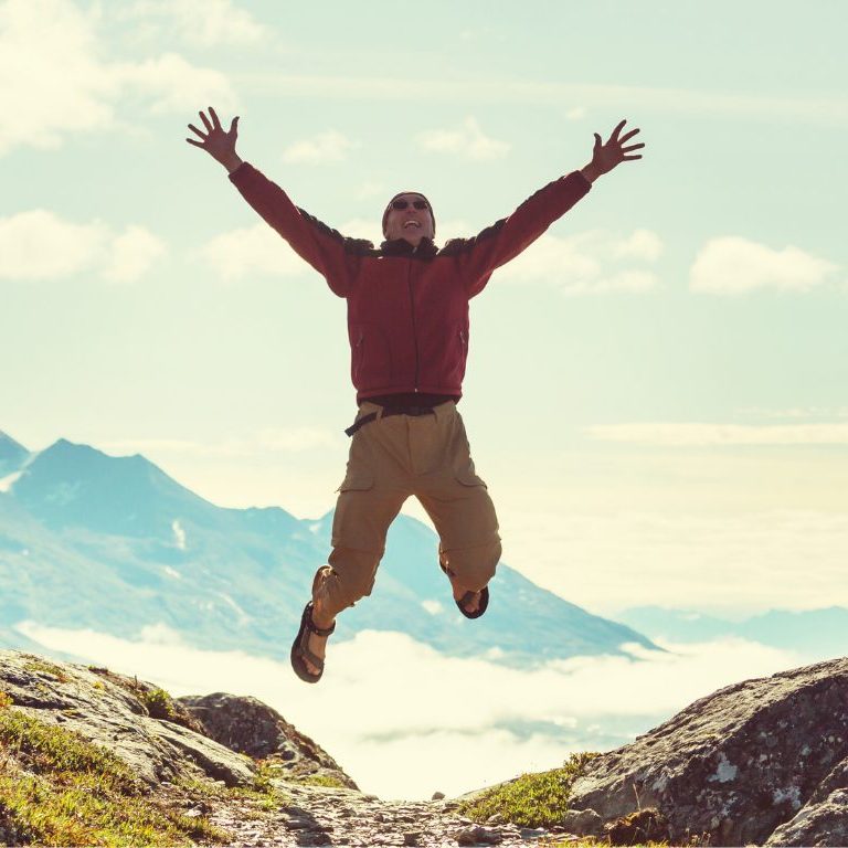 man jumping up looking at a mountain view