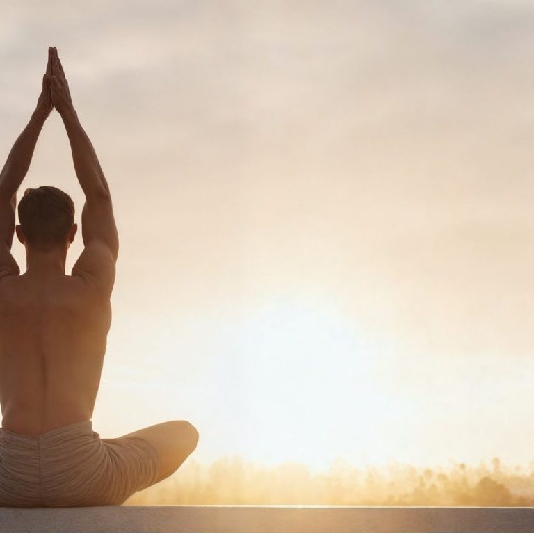 man meditating to the sunrise